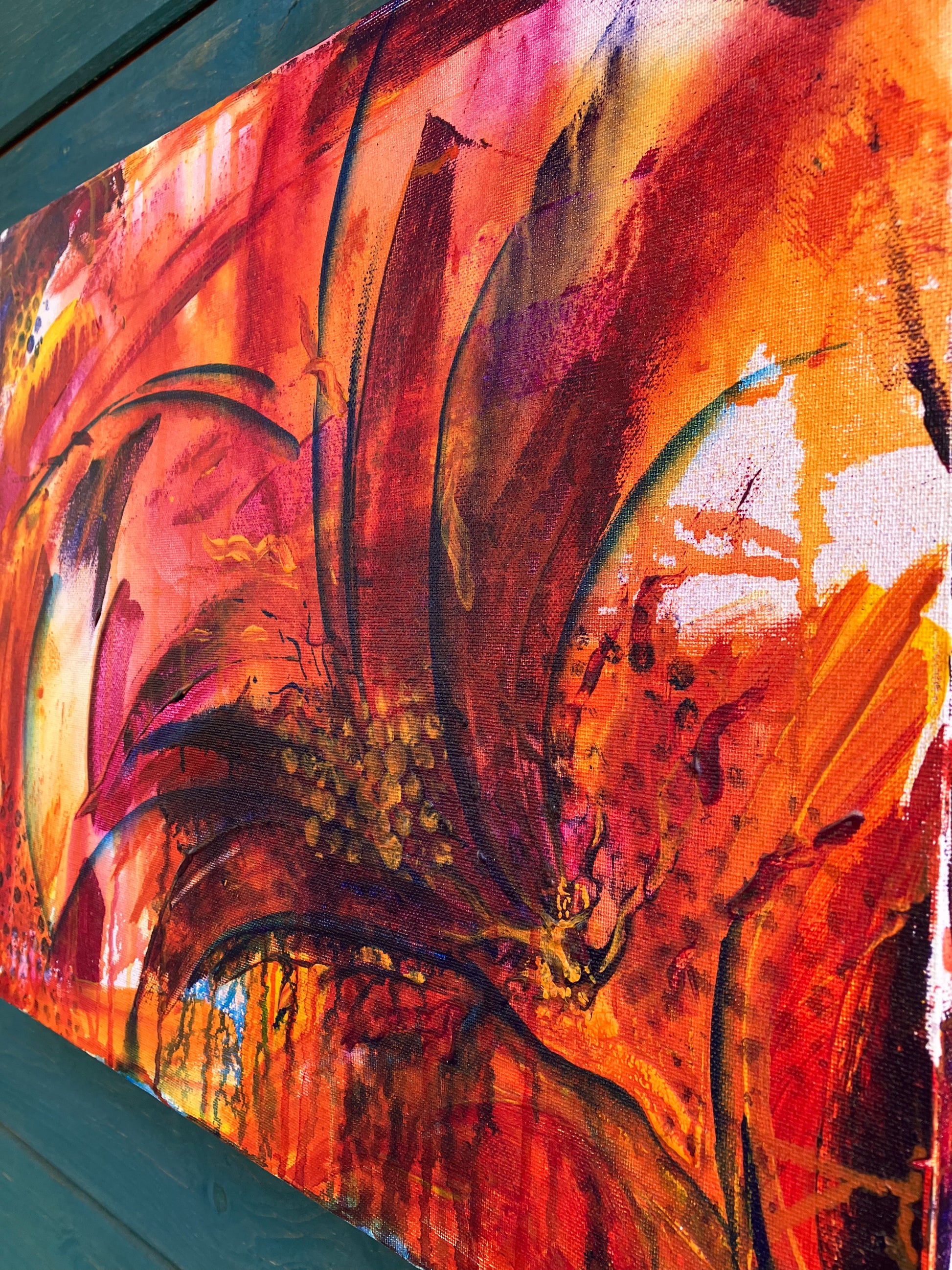 Close up of detail of fiery abstract floral artwork with bold red, orange, and magenta tones, featuring dynamic petal shapes and expressive brushwork that radiates movement and vitality.