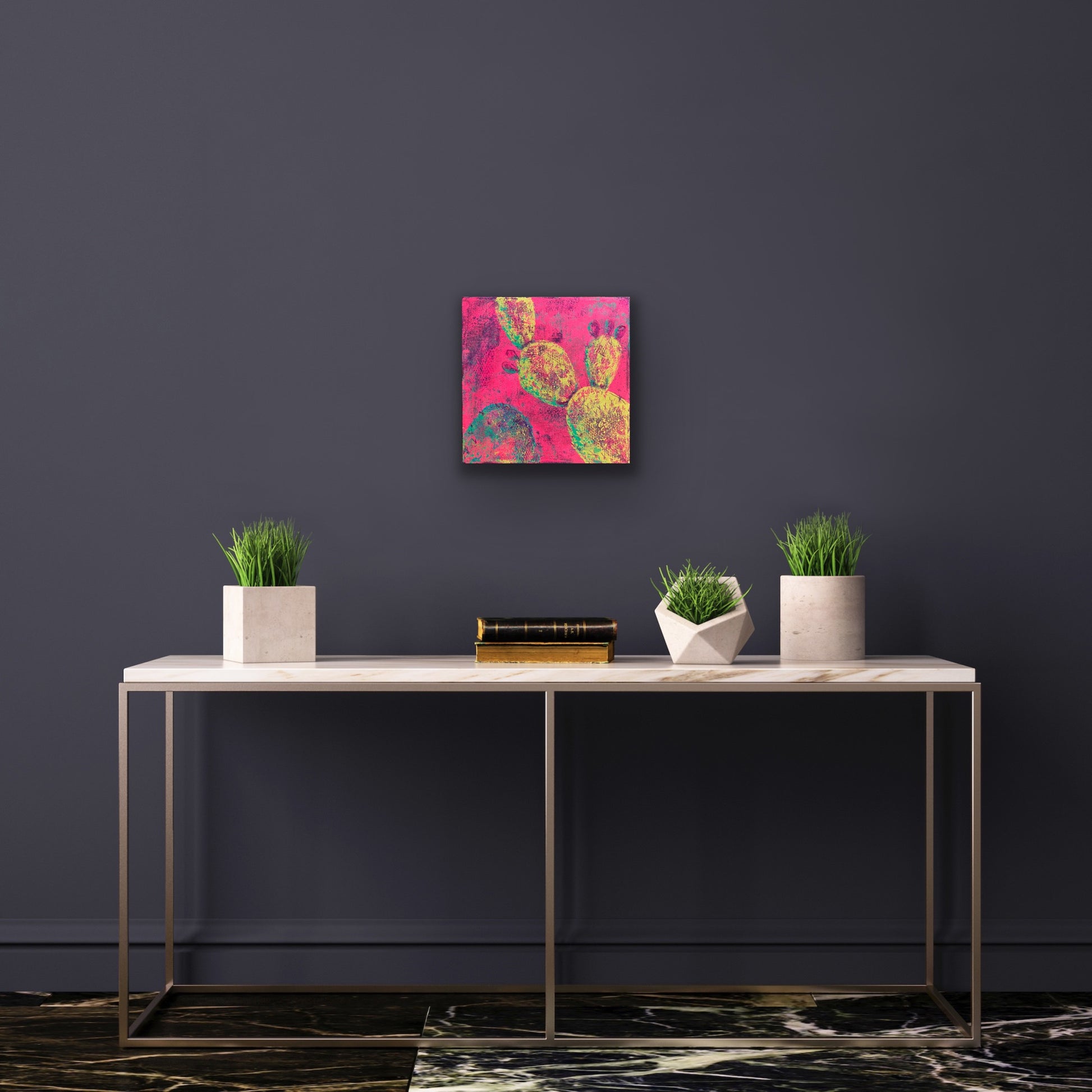 In situ photo of a bright abstract desert cactus painting with neon yellow prickly pear pads on a vivid pink background, symbolizing new growth and early spring bloom.