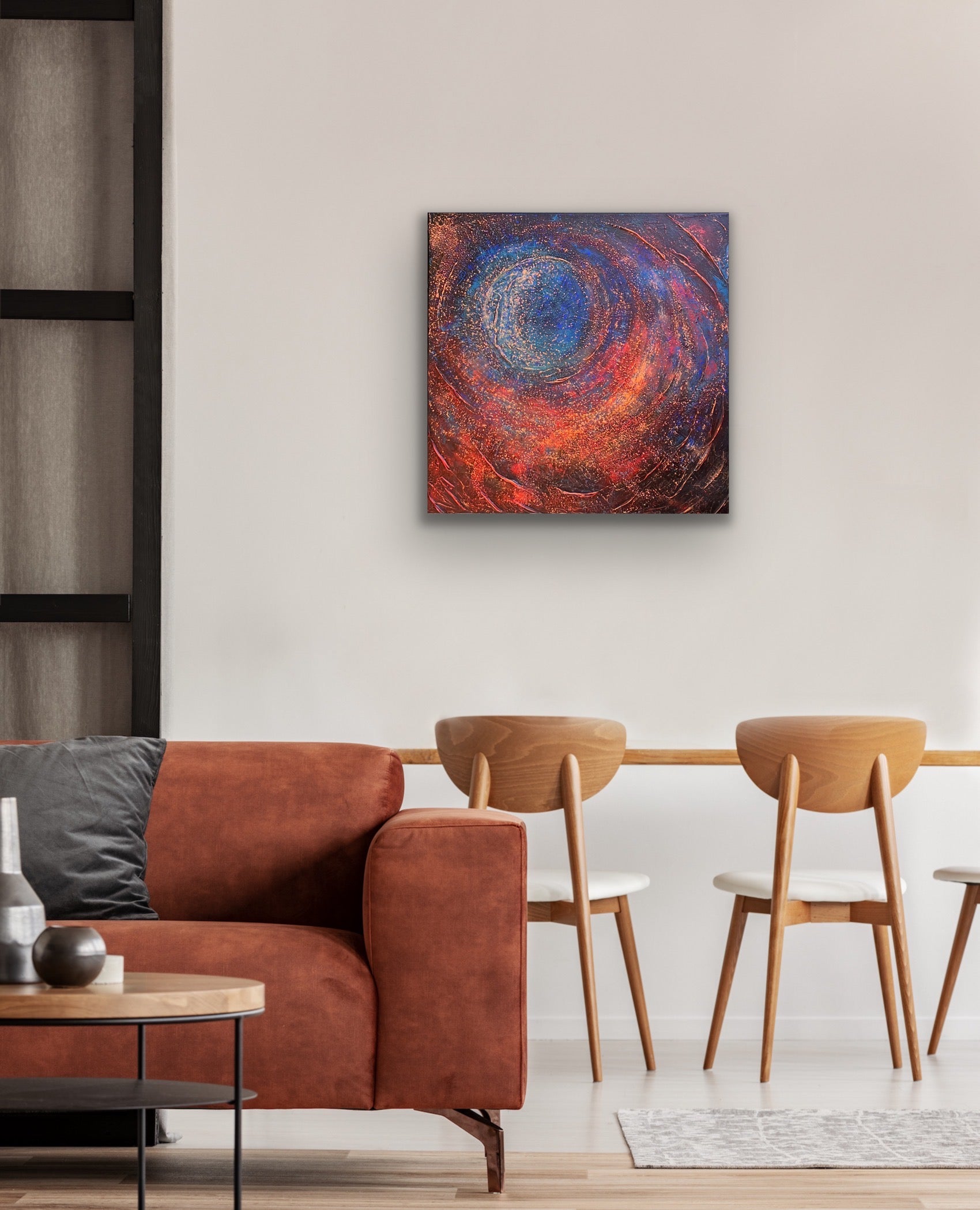 An in situ photo of Enough – a textured acrylic abstract painting with a central spiral design in blues, reds, and golds, evoking cosmic or galaxy-like movement.