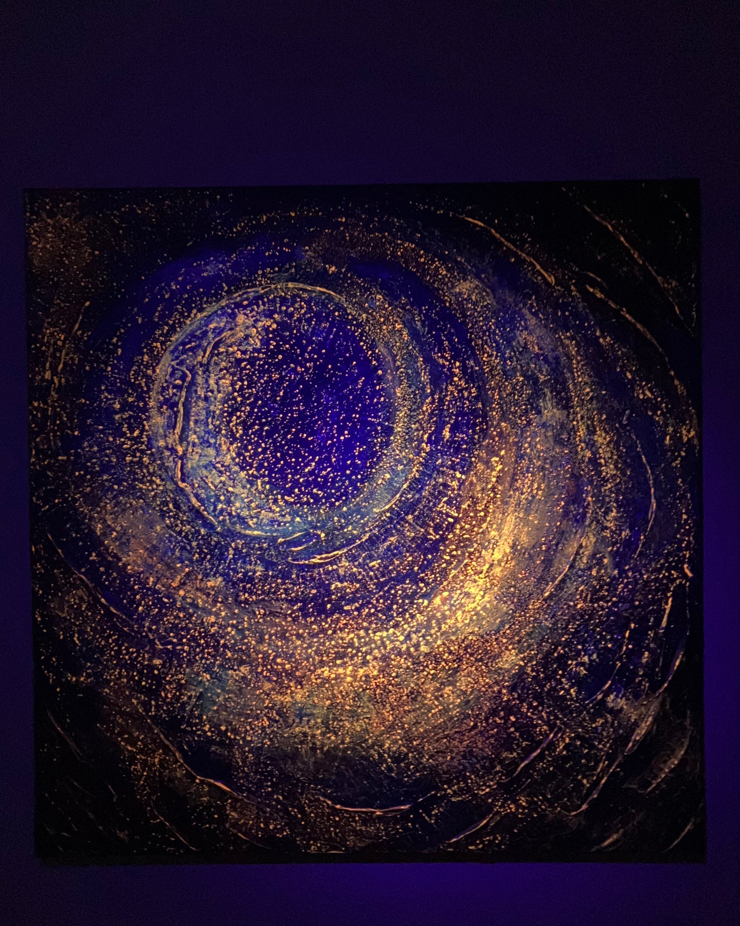 Enough – a textured acrylic abstract painting with a central spiral design in blues, reds, and golds, evoking cosmic or galaxy-like movement, glowing under a blacklight.