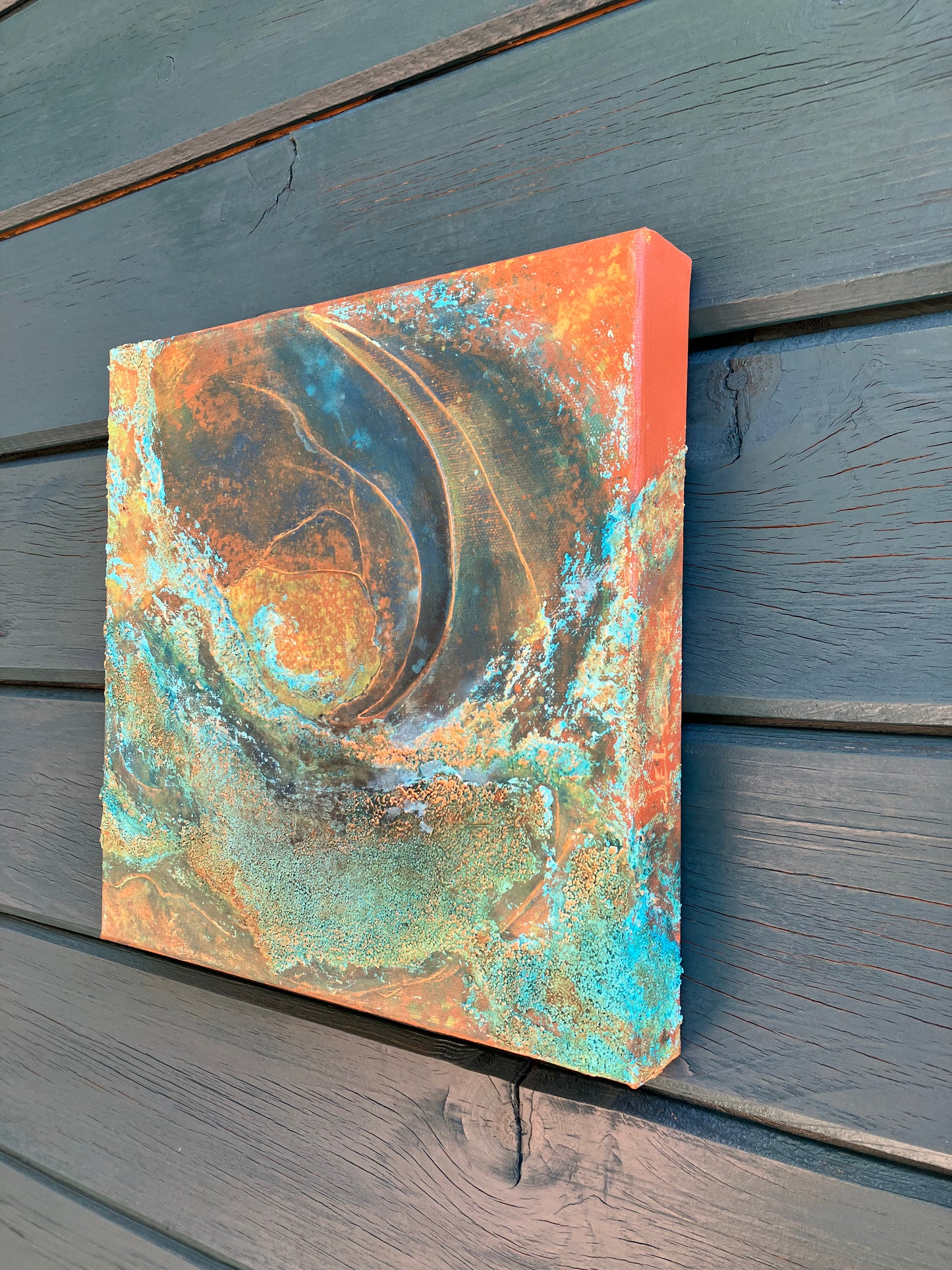 Close up showing detail of earth-inspired abstract painting with rust, teal, and copper tones, featuring layered organic textures that evoke landscapes, topography, or mineral formations.