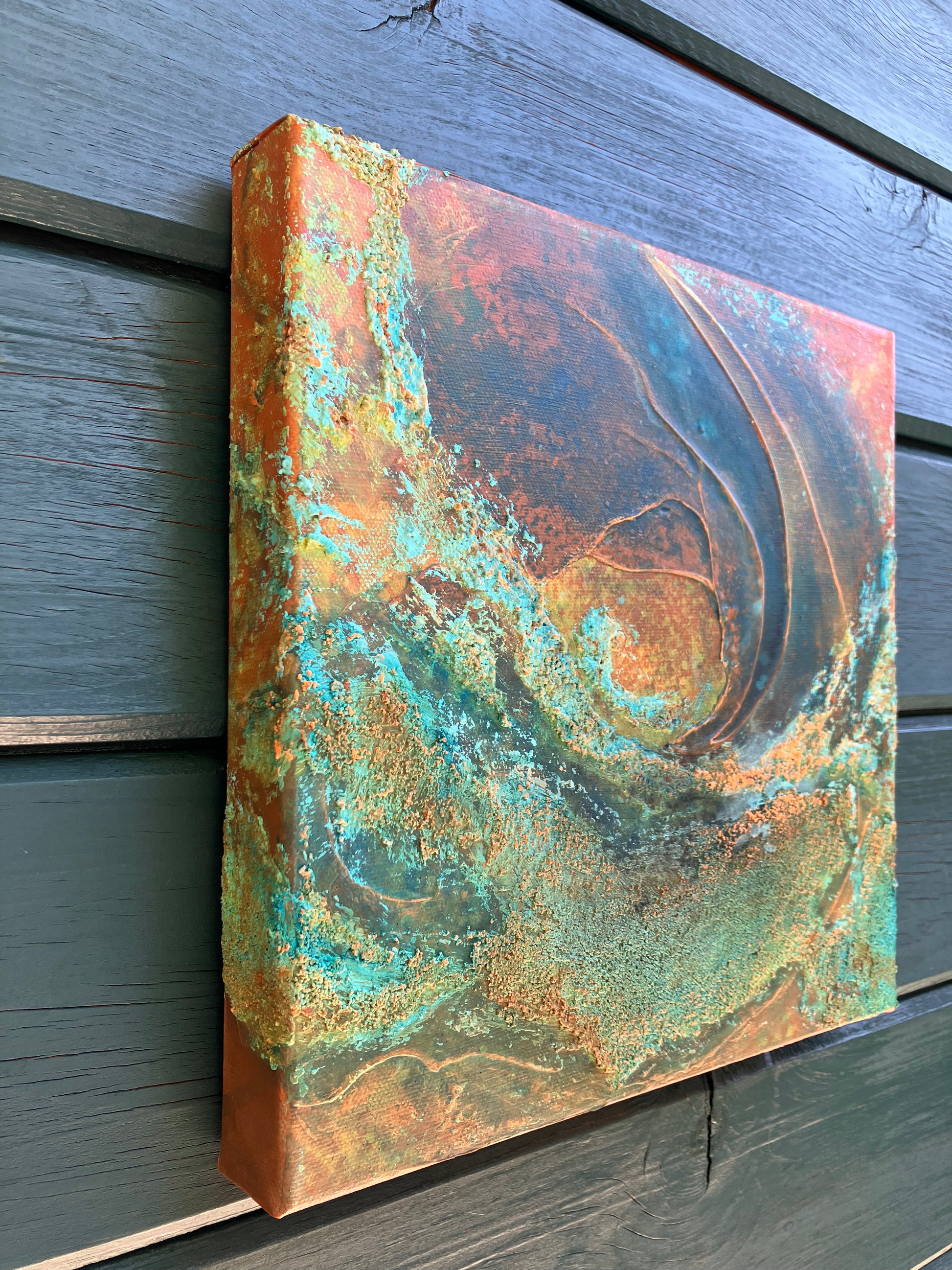 Close up showing detail of earth-inspired abstract painting with rust, teal, and copper tones, featuring layered organic textures that evoke landscapes, topography, or mineral formations.
