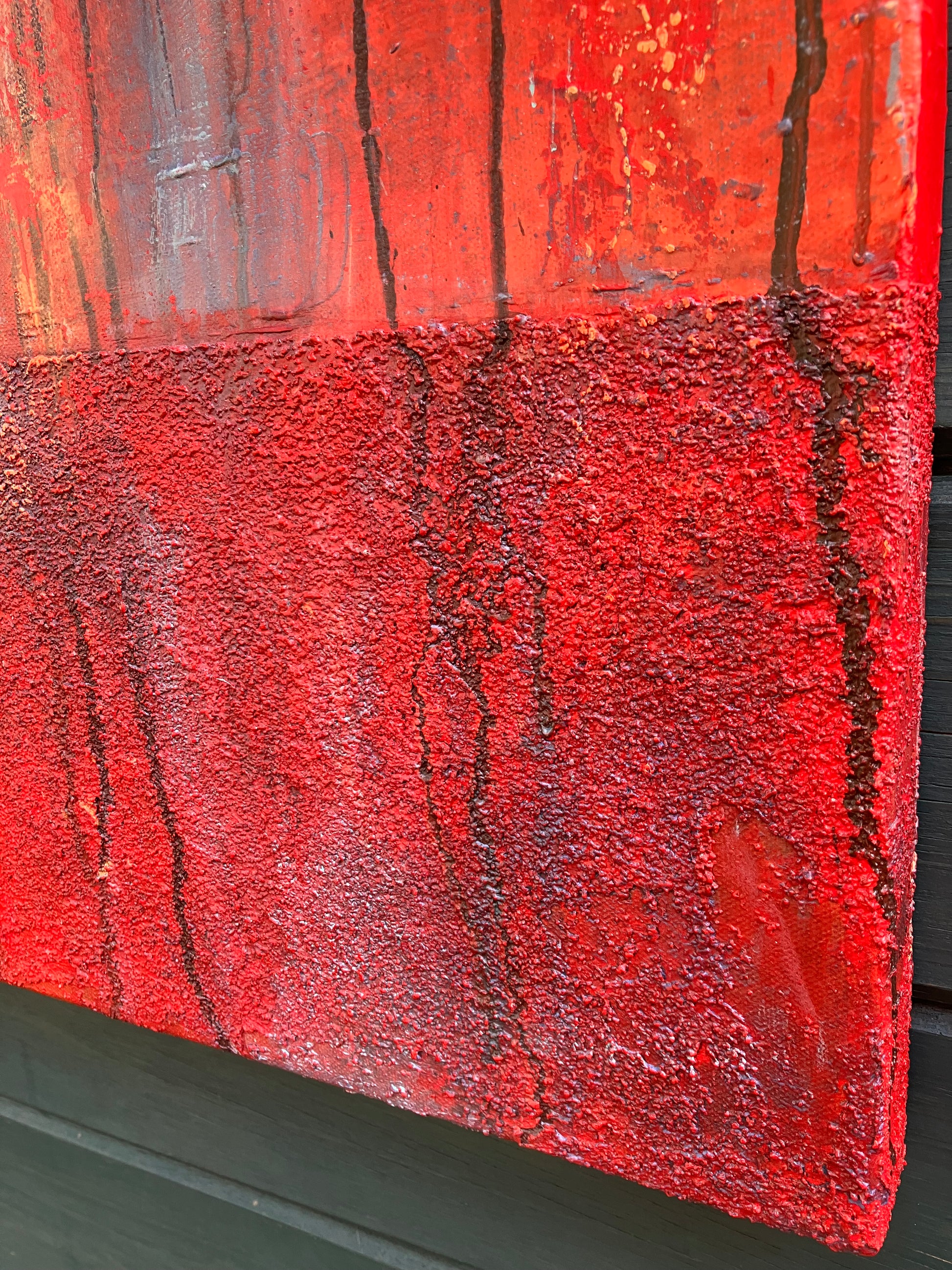 Close up of texture in original abstract painting titled Surrender, featuring intense vertical drips and swirls of red, blue, and orange with the word “PEACE” subtly stenciled and slightly off-center. Rich texture and bold color transitions create emotional depth.
